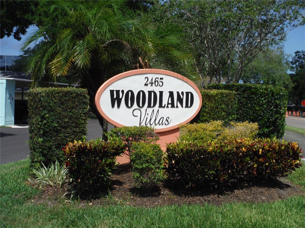 The exterior of a single-story house features a covered porch, light-colored stucco walls, and landscaping — 2465 NORTHSIDE DRIVE UNIT 1901, CLEARWATER, FL