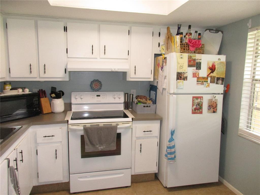 A kitchen features white cabinets, a white stove, a white refrigerator, and gray countertops — 2465 NORTHSIDE DRIVE UNIT 1901, CLEARWATER, FL