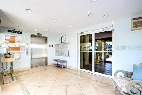 A bright lobby features tile flooring, a metal elevator, mailboxes, and glass entry doors — 7872 SAILBOAT KEY BOULEVARD S UNIT 405, SOUTH PASADENA, FL