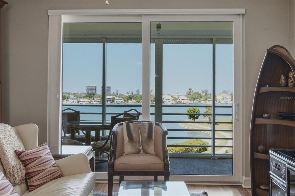 A living room with a sliding glass door overlooking a balcony and a waterfront view — 7872 SAILBOAT KEY BOULEVARD S UNIT 405, SOUTH PASADENA, FL