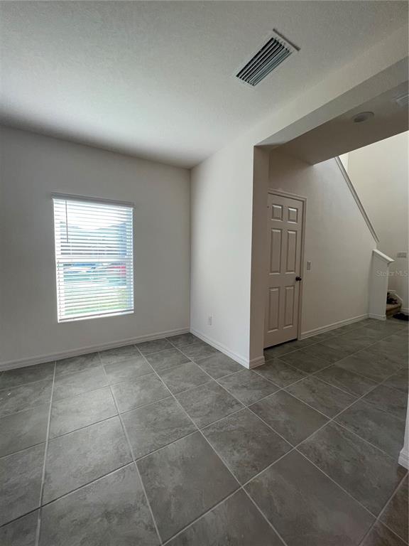 A room with gray tile flooring, a window with blinds, and a closed white door — 435 ANNABELLE WAY, DAVENPORT, FL