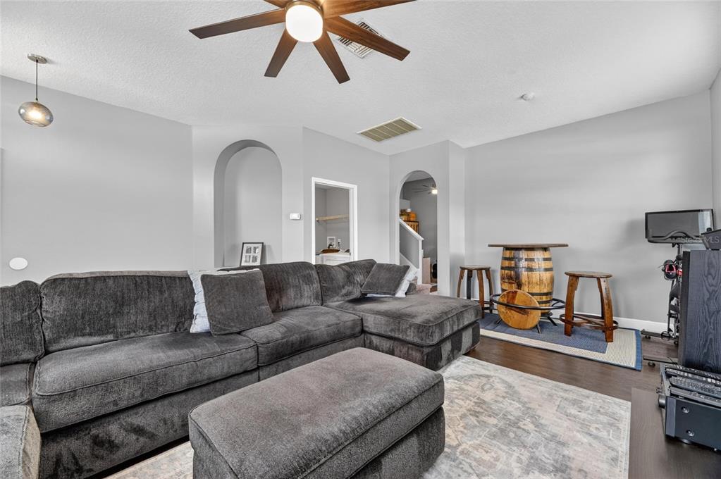 A living room features a large gray sectional, a barrel-style table, and arched doorways — 11207 VILLAGE BROOK DRIVE, RIVERVIEW, FL