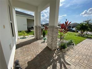 A covered front porch features stone-clad pillars and herringbone-patterned brick pavers — 247 SPARROW HAWK DRIVE, GROVELAND, FL