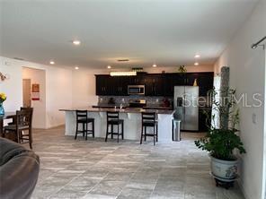 A kitchen with dark cabinets, a large island with bar seating, and light-colored tile flooring — 247 SPARROW HAWK DRIVE, GROVELAND, FL
