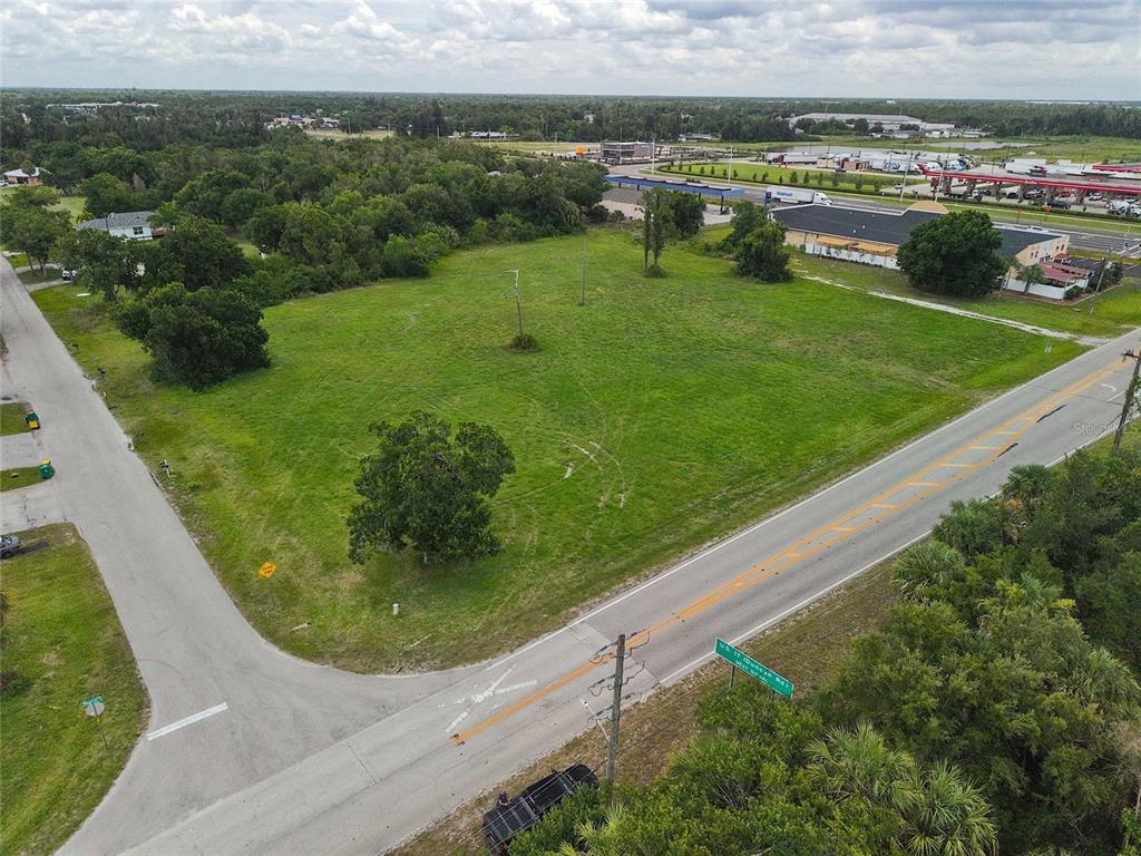 An aerial view shows a large, grassy vacant lot situated at a road intersection — 3700 BAYSWATER DRIVE, PUNTA GORDA, FL
