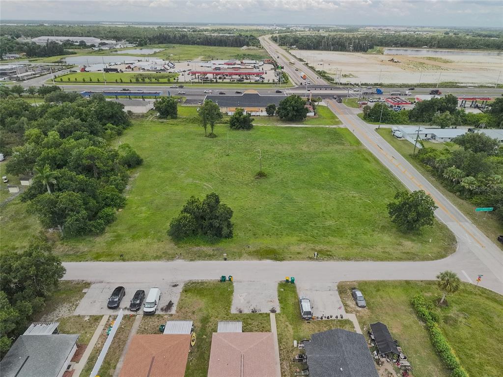 An aerial view shows a large, vacant grassy lot bordered by roads and residential houses — 3700 BAYSWATER DRIVE, PUNTA GORDA, FL