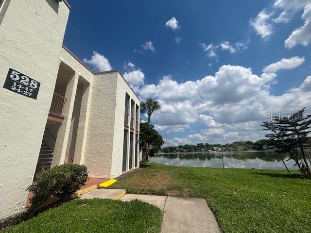A low-rise apartment building exterior stands next to a grassy lawn and a lake — 528 ORANGE DRIVE UNIT 26, ALTAMONTE SPRINGS, FL