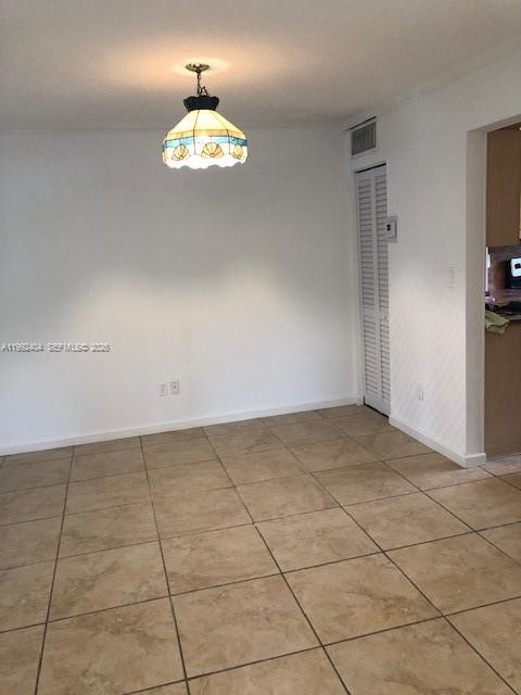 An empty dining area features a stained-glass pendant light and beige tile flooring — 6713 SW 112th Ct, Miami FL 33173, MIAMI, FL