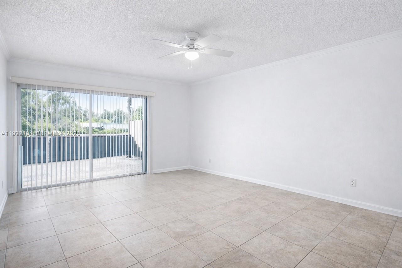An empty room features white walls, beige tile flooring, a ceiling fan, and sliding glass doors — 6713 SW 112th Ct, Miami FL 33173, MIAMI, FL