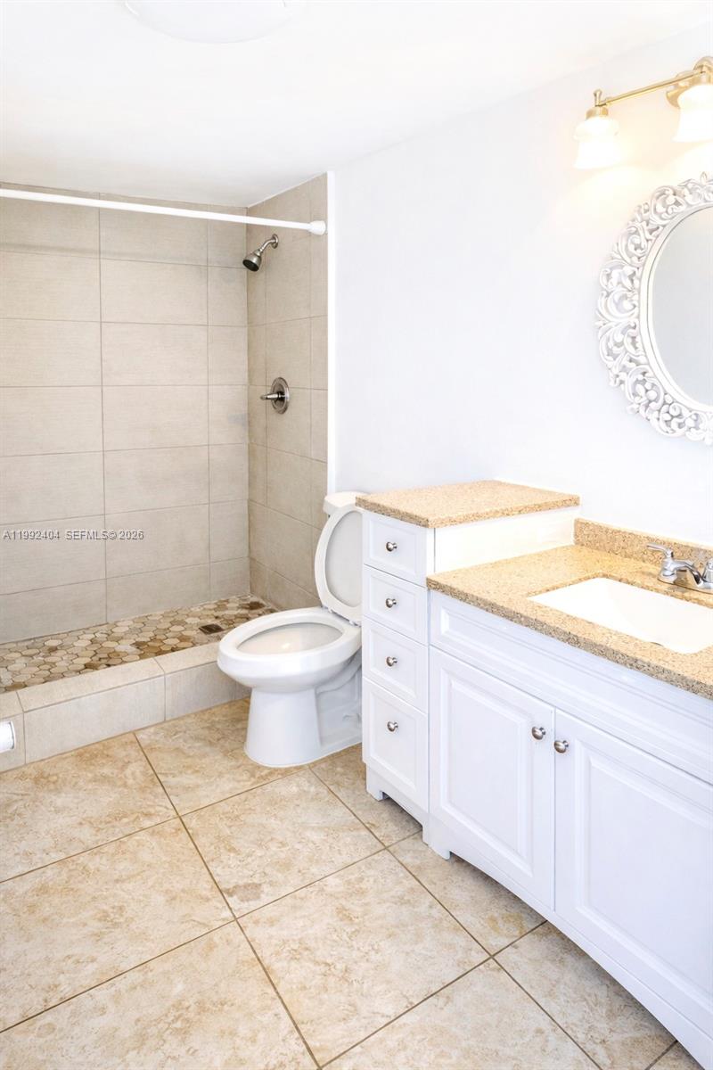 A bathroom features a walk-in shower, a white vanity with a speckled countertop, and tile flooring — 6713 SW 112th Ct, Miami FL 33173, MIAMI, FL
