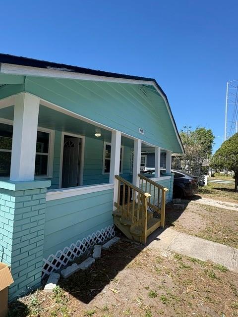 A turquoise house exterior features a covered front porch with wooden steps and railings — 408 N MARTIN LUTHER KING JR AVENUE, CLEARWATER, FL