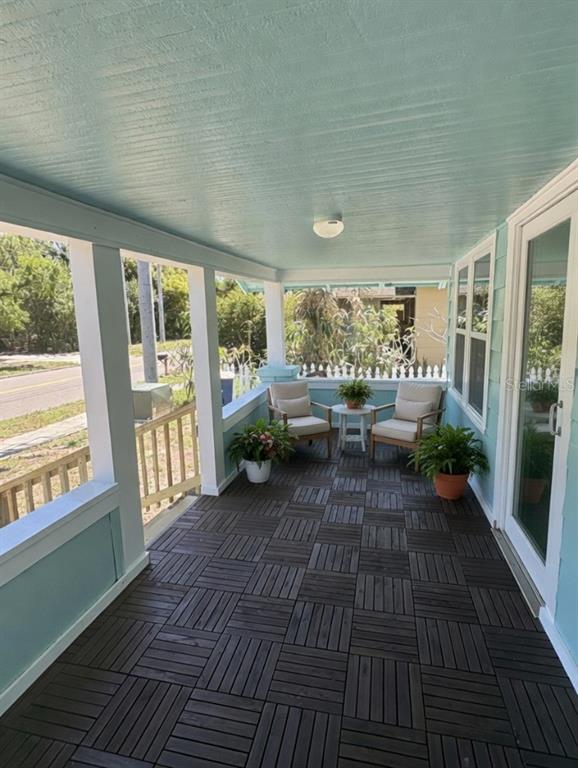 A covered porch with light blue walls, dark wood-look floor tiles, and two outdoor chairs — 408 N MARTIN LUTHER KING JR AVENUE, CLEARWATER, FL