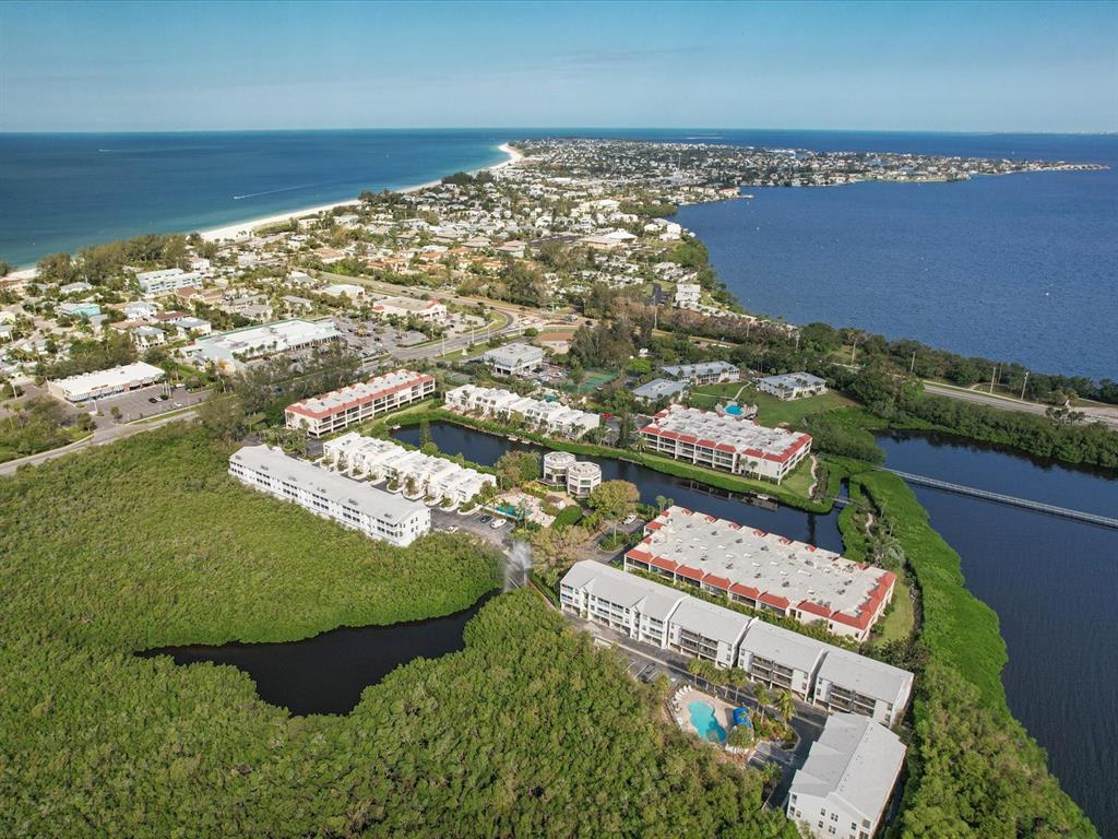Aerial view of a coastal residential complex surrounded by mangroves, water, and a sandy beach — 3607 E BAY DRIVE UNIT 206, BRADENTON BEACH, FL