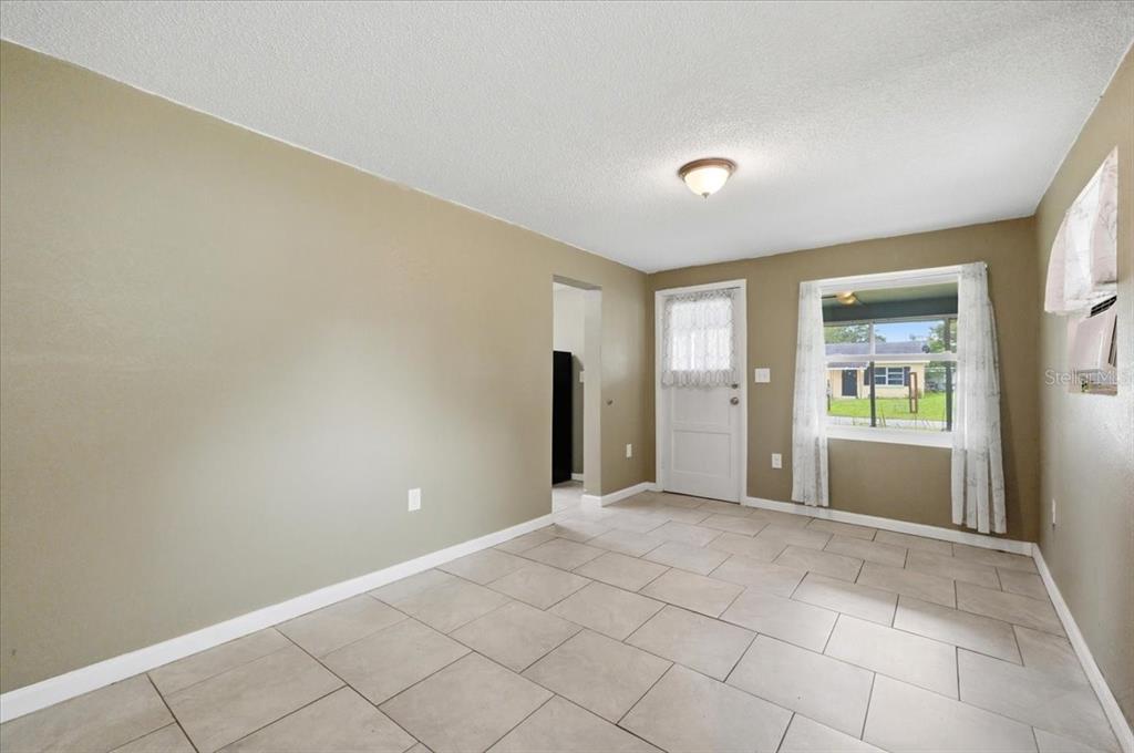 A room with beige walls, light-colored tile flooring, a white door, and a window — 2418 JUNGLE STREET, LAKELAND, FL
