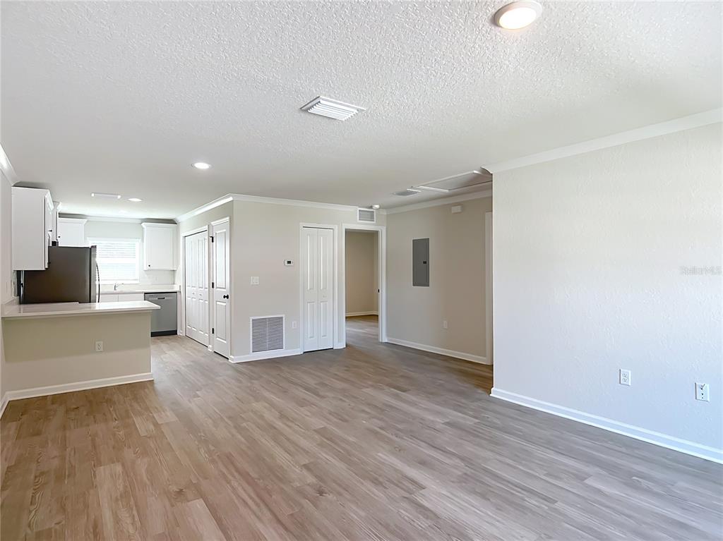 An open-concept living area features light wood-look flooring, neutral walls, and an adjacent kitchen — 15845 SW 33RD AVENUE ROAD, OCALA, FL