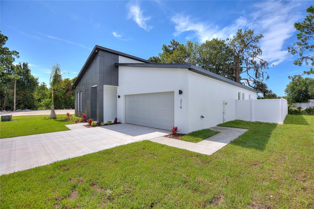 A modern single-story house with a white stucco exterior, dark gray accent wall, and garage — 24479 SW KINGSWAY CIRCLE, ARCADIA, FL