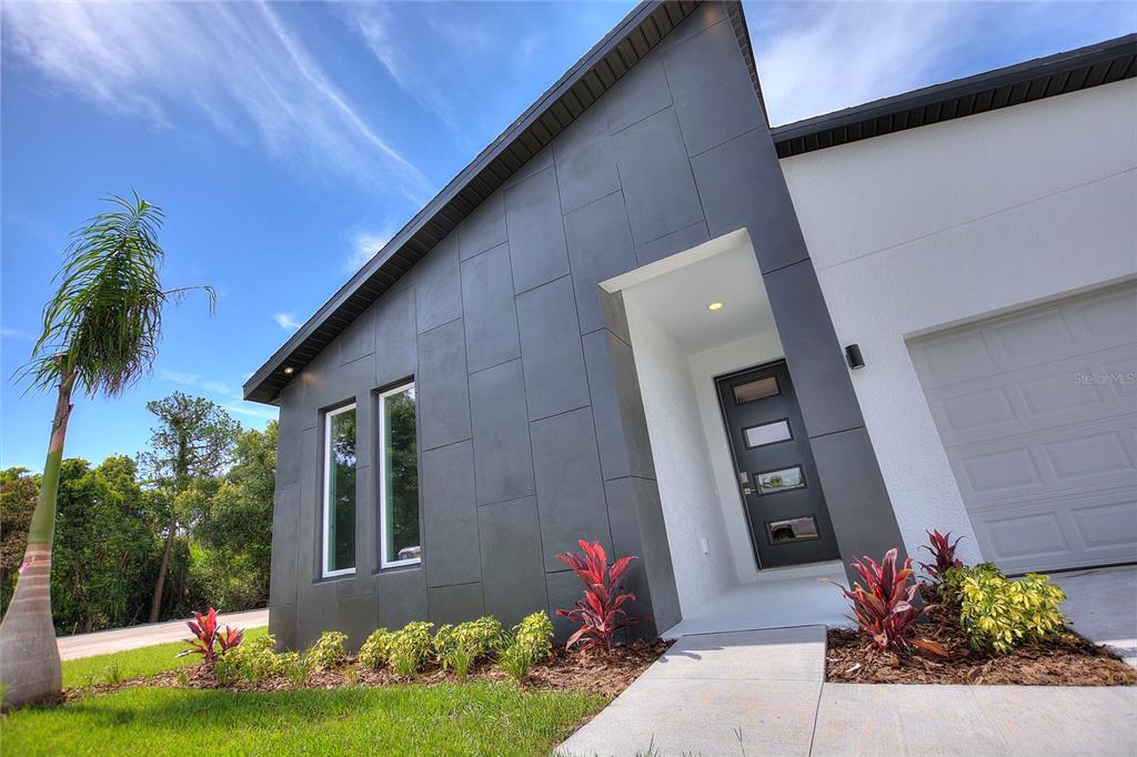A modern home exterior features dark gray paneling, a white garage, and a front entrance — 24479 SW KINGSWAY CIRCLE, ARCADIA, FL