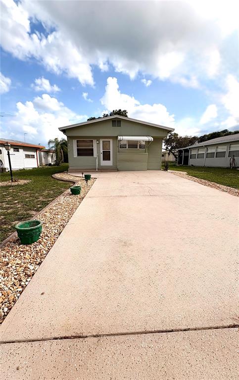 A light green single-story house features a concrete driveway and a small front porch — 117 SADDLEBAG TRAIL, LAKE WALES, FL