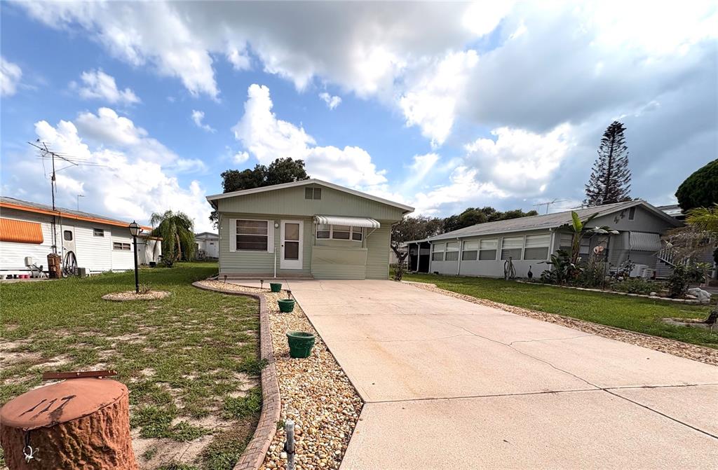 A light green manufactured home with a concrete driveway and a gravel landscaping border — 117 SADDLEBAG TRAIL, LAKE WALES, FL
