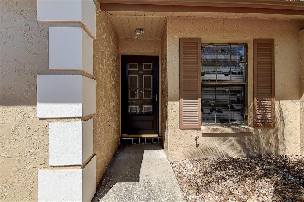A front entryway features a dark door with glass panels, a window with shutters, and stucco — 4752 SUNNY LOOP, HOLIDAY, FL
