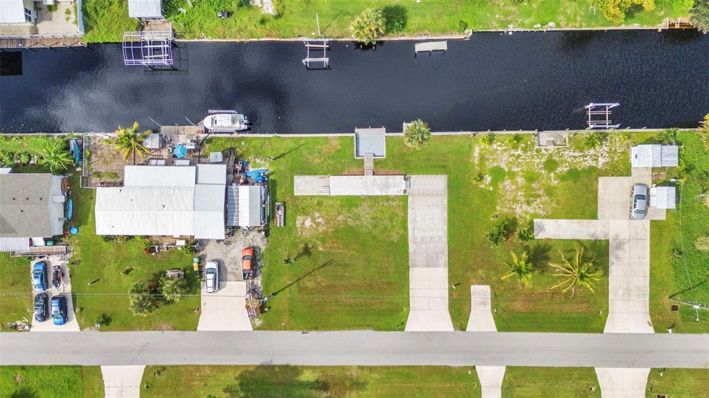 An aerial view shows a waterfront property with a house, driveway, and boat dock — 4177 HOLLIS AVENUE, PORT CHARLOTTE, FL
