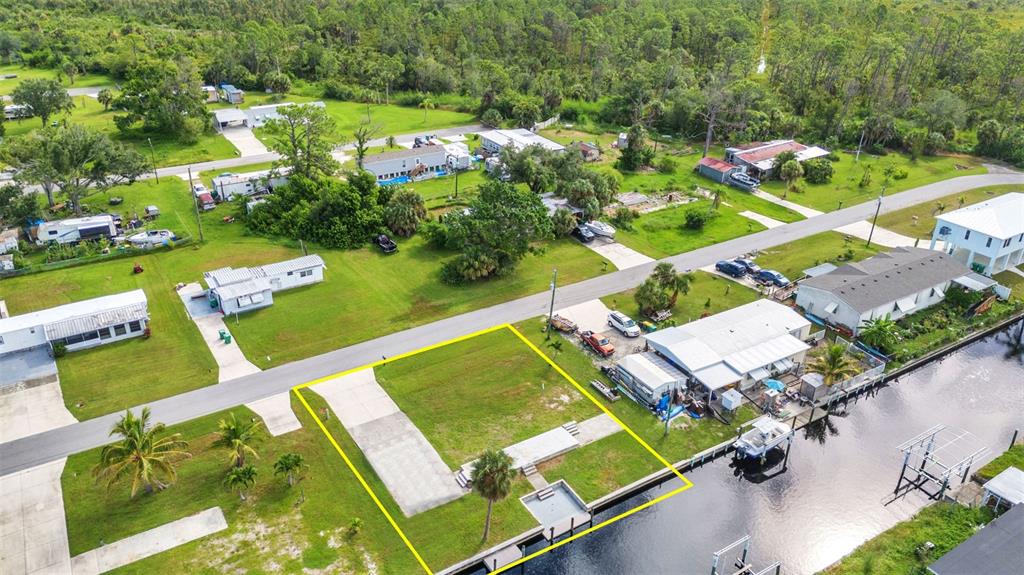 An aerial view of a vacant waterfront lot with a concrete driveway and boat dock — 4177 HOLLIS AVENUE, PORT CHARLOTTE, FL