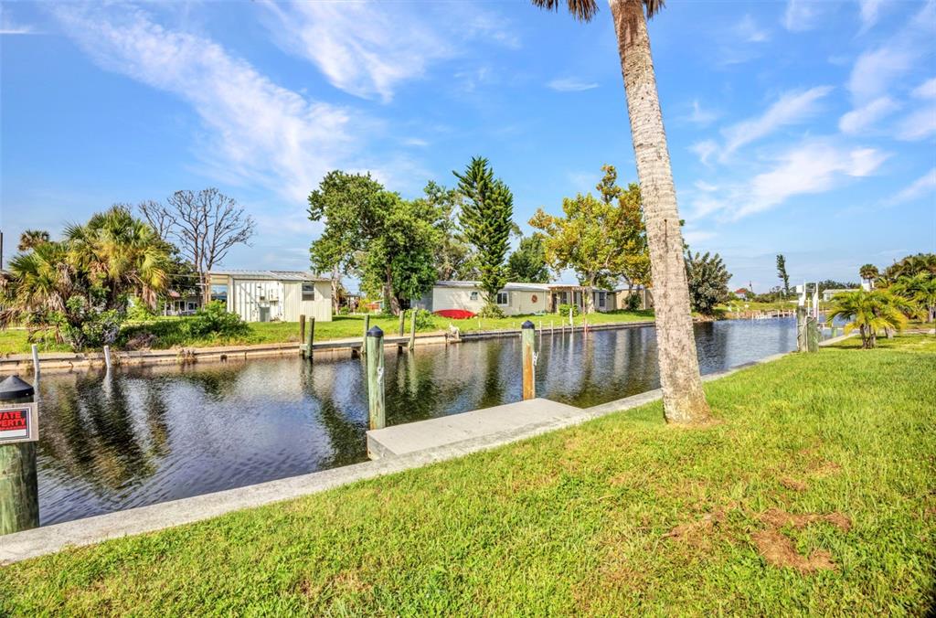 A canal flows between grassy banks with boat docks and small homes in the background — 4177 HOLLIS AVENUE, PORT CHARLOTTE, FL