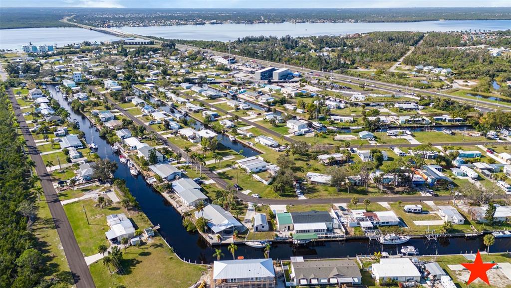 An aerial view of a residential neighborhood featuring houses along canals leading to a bay — 4177 HOLLIS AVENUE, PORT CHARLOTTE, FL