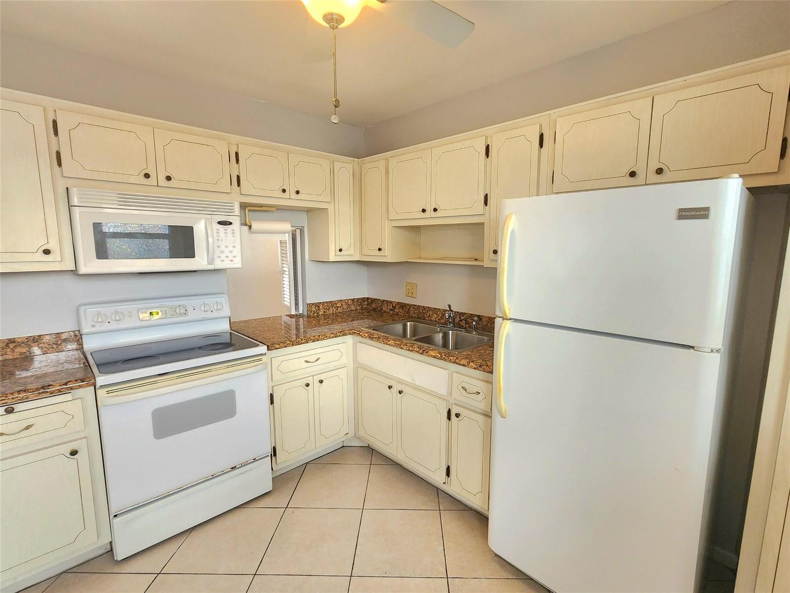 A kitchen with white cabinets, white appliances, and brown granite countertops over tiled flooring — 2223 Park Lane # 105, Hollywood FL 33021, HOLLYWOOD, FL