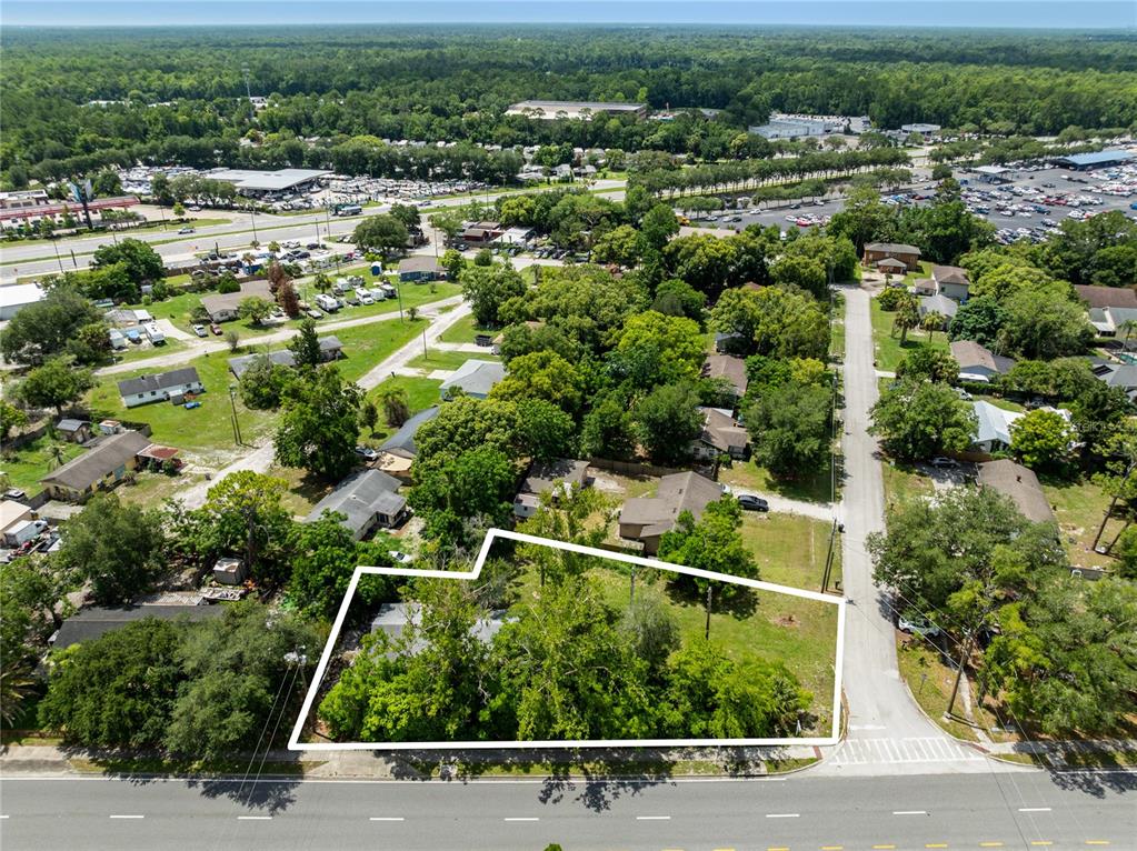 An aerial view shows a wooded residential lot outlined in white along a paved road — 3711 N RONALD REAGAN BOULEVARD, LONGWOOD, FL