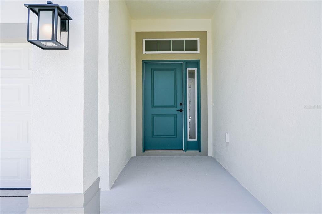 A teal front door with a side light and transom window sits under a covered porch — 3139 NE 45TH AVENUE, OCALA, FL