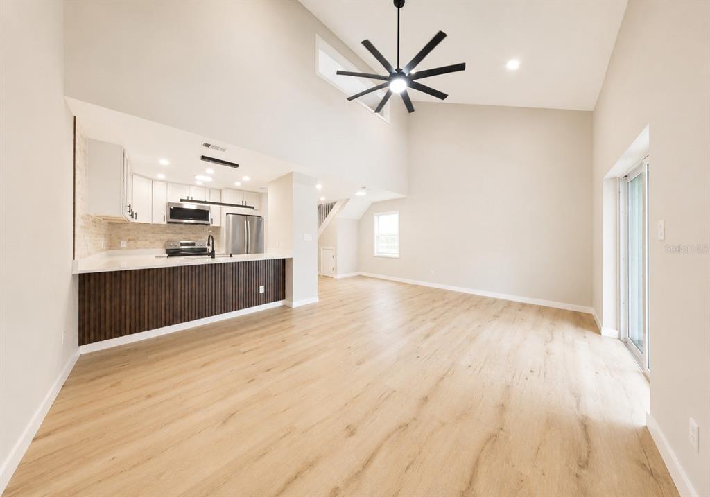 A kitchen with white cabinets and a slatted island overlooks an open living area — 1141 WOODMAN WAY, ORLANDO, FL
