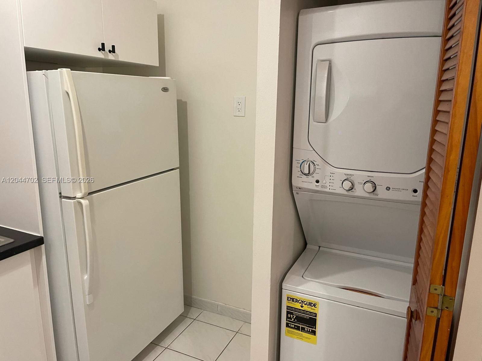 A white refrigerator stands next to a stacked washer and dryer unit in a kitchen — 10101 W Okeechobee Rd # 5202, Hialeah Gardens FL 33016, HIALEAH GARDENS, FL