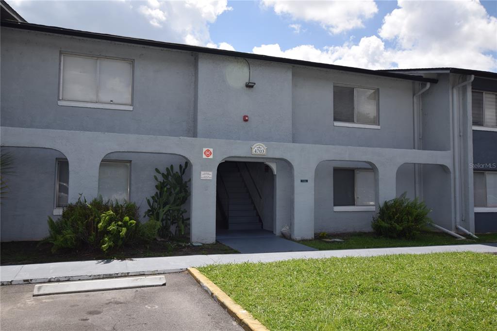 A two-story apartment building exterior features a central staircase and arched covered entryway — 4703 S TEXAS AVENUE UNIT 4703A, ORLANDO, FL