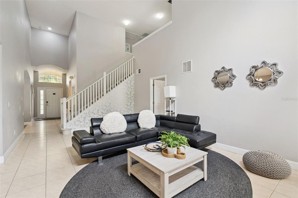 A living room features a black sectional sofa, a coffee table, and a staircase — 2694 LA ISLA COURT, KISSIMMEE, FL