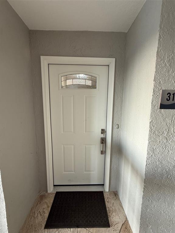 A white front door with a glass insert is set in a textured gray entryway — 1477 PARK BEACH CIRCLE UNIT 31, PUNTA GORDA, FL