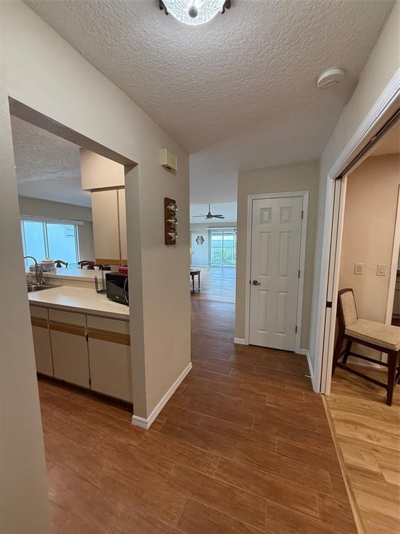 A hallway with tile flooring leads to a living area, with a kitchen visible left — 1477 PARK BEACH CIRCLE UNIT 31, PUNTA GORDA, FL