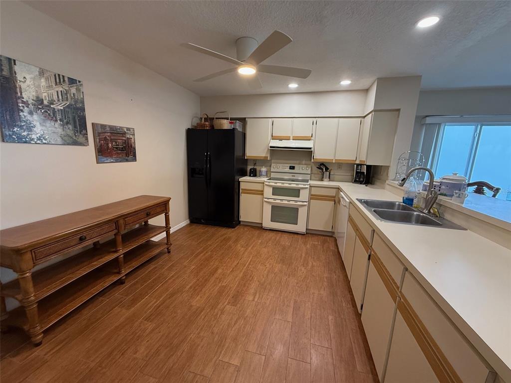 A kitchen features white cabinets, a black refrigerator, a white stove, and wood-look flooring — 1477 PARK BEACH CIRCLE UNIT 31, PUNTA GORDA, FL