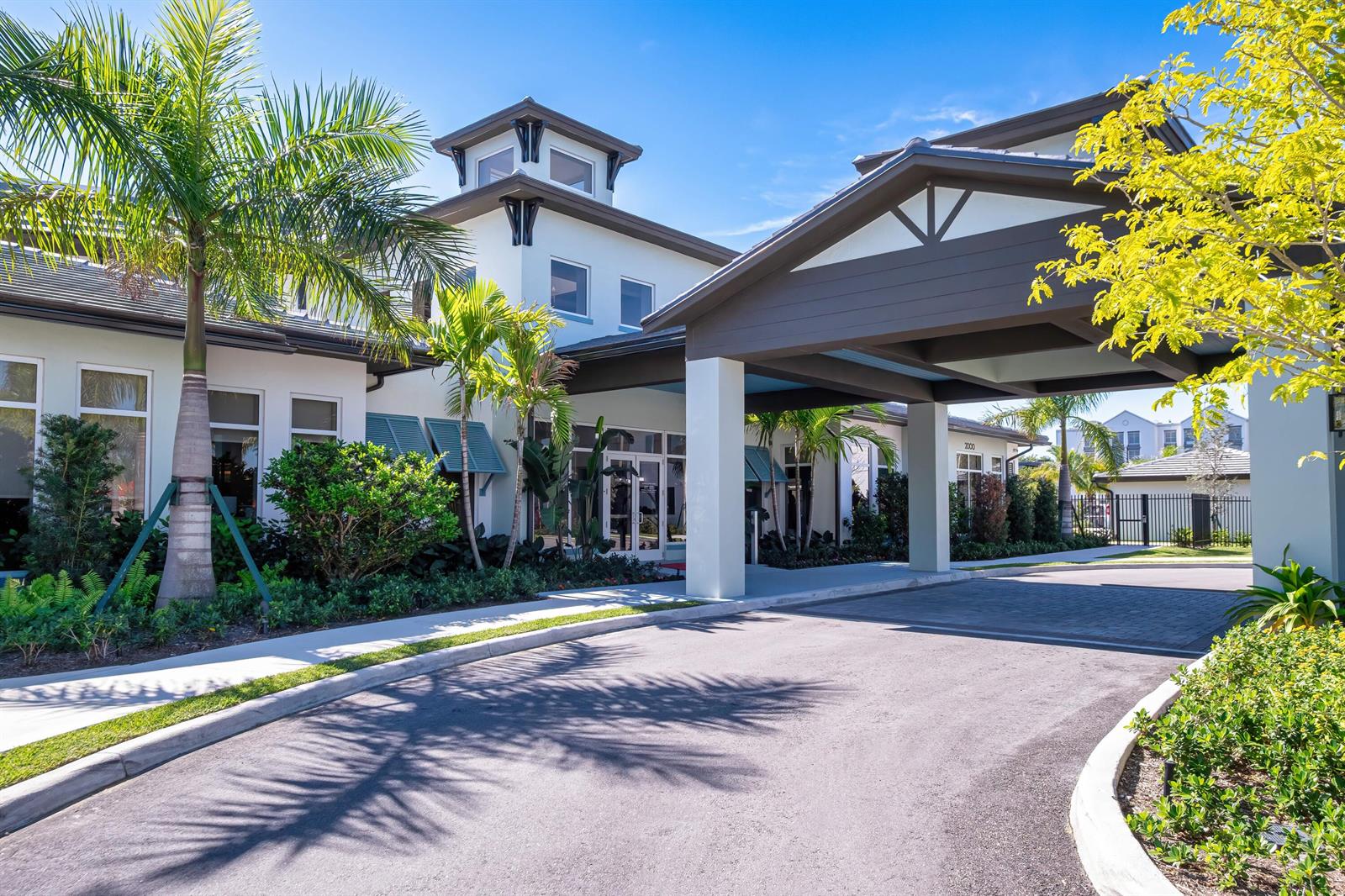 A modern building exterior features a covered porte-cochère, palm trees, and a paved driveway — 2000 Stirling Road # 104, Hollywood FL 33020, HOLLYWOOD, FL