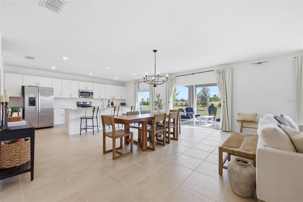 An open-concept kitchen and dining area features white cabinetry, a wooden table, and tile flooring — 1017 CALICO POINTE CIRCLE, GROVELAND, FL