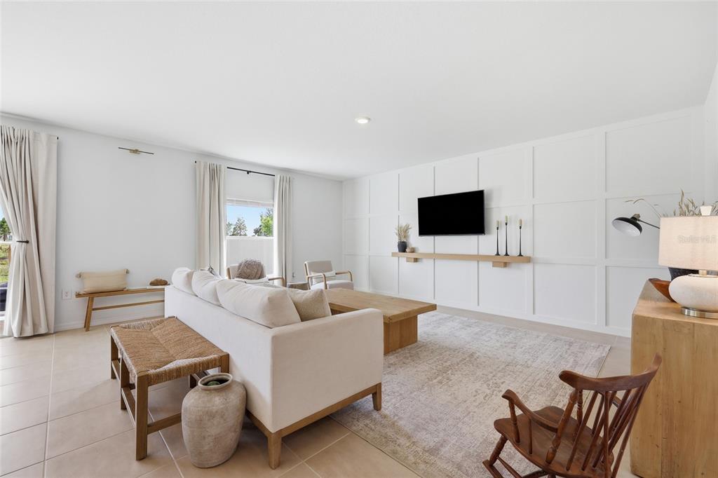 A living room features a white paneled accent wall, a television, and neutral-toned furniture — 1017 CALICO POINTE CIRCLE, GROVELAND, FL