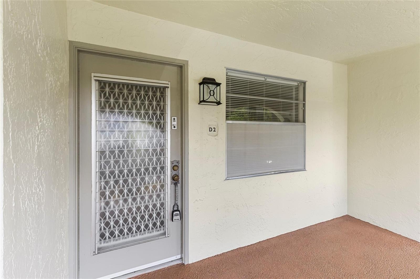 A beige exterior entryway features a gray door with a decorative glass insert and window — 2701 Nassau Bend # D2, Coconut Creek FL 33066, COCONUT CREEK, FL