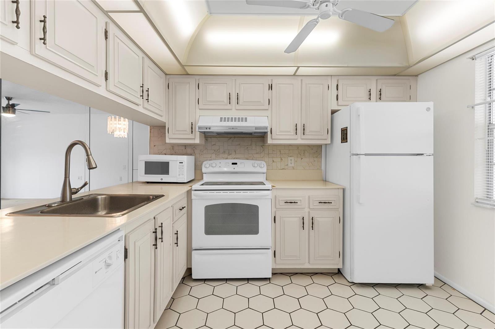 A kitchen with white cabinets, white appliances, a stainless steel sink, and hexagonal floor tiles — 2701 Nassau Bend # D2, Coconut Creek FL 33066, COCONUT CREEK, FL