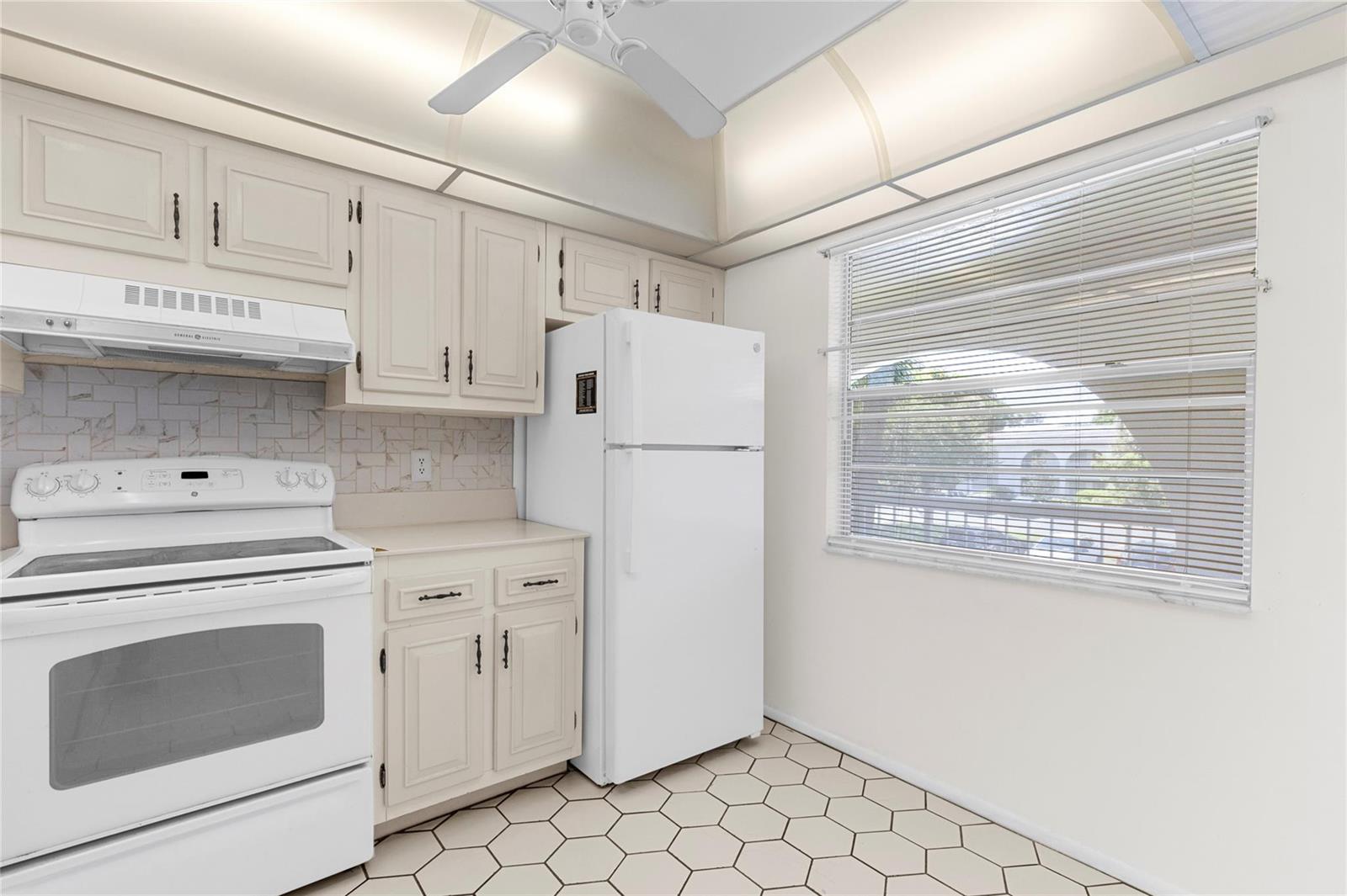 A kitchen features white appliances, light-colored cabinets, a tiled backsplash, and hexagonal floor tiles — 2701 Nassau Bend # D2, Coconut Creek FL 33066, COCONUT CREEK, FL