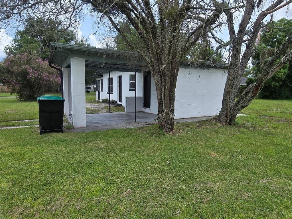 A white concrete block house features a covered carport and a large tree in the yard — 5762 DOGWOOD DRIVE, ORLANDO, FL