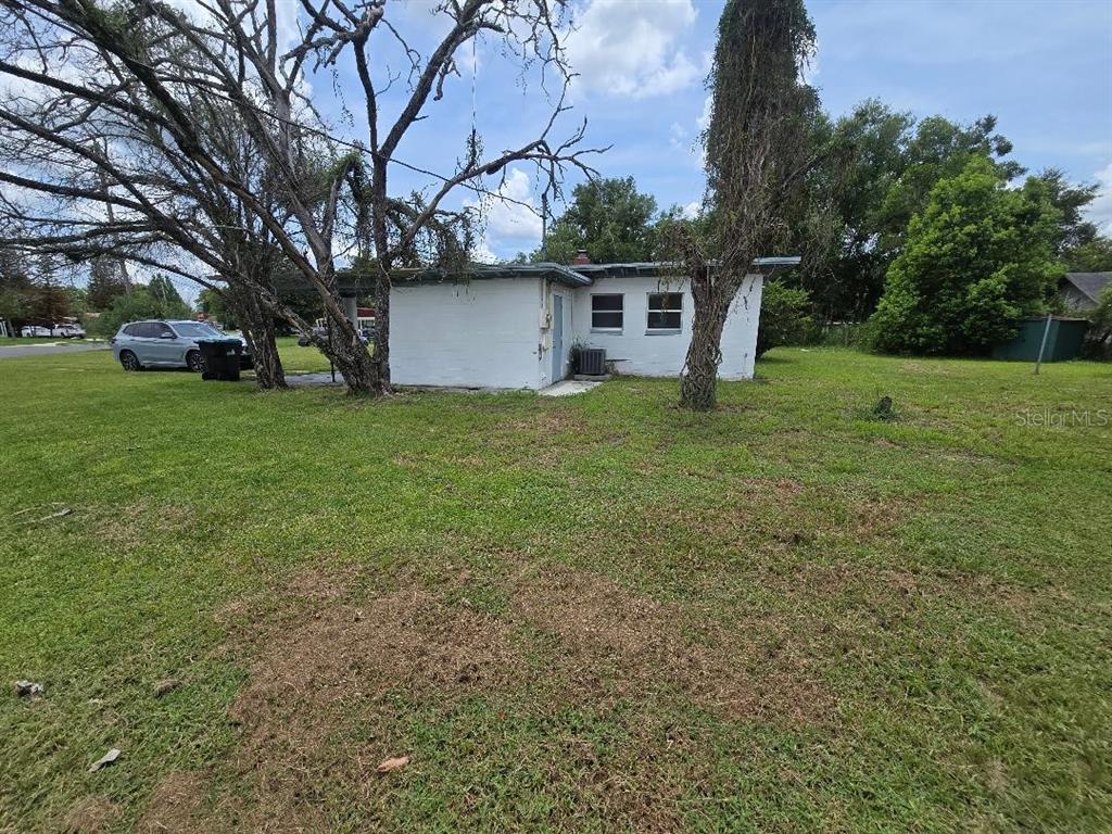 A white, single-story house exterior sits on a grassy lot with large trees — 5762 DOGWOOD DRIVE, ORLANDO, FL