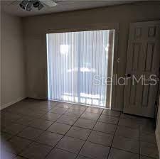 A room with beige tile flooring, vertical blinds on a sliding door, and a door — 3810 W SAN CARLOS STREET UNIT 314, TAMPA, FL