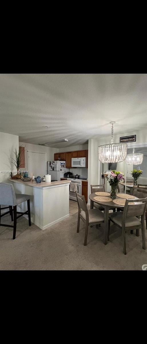 A dining area with a beaded chandelier sits adjacent to a kitchen with wood cabinets — 14890 pleasant bay lane # 3102, Naples FL 34119, NAPLES, FL