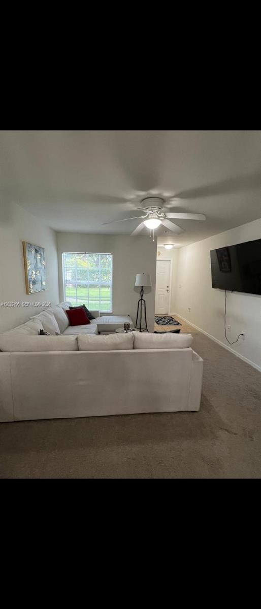 A living room features a large white sectional sofa, a ceiling fan, and a wall-mounted television — 14890 pleasant bay lane # 3102, Naples FL 34119, NAPLES, FL