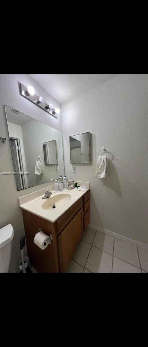 A bathroom features a wooden vanity with a beige countertop, a large mirror, and tile flooring — 14890 pleasant bay lane # 3102, Naples FL 34119, NAPLES, FL